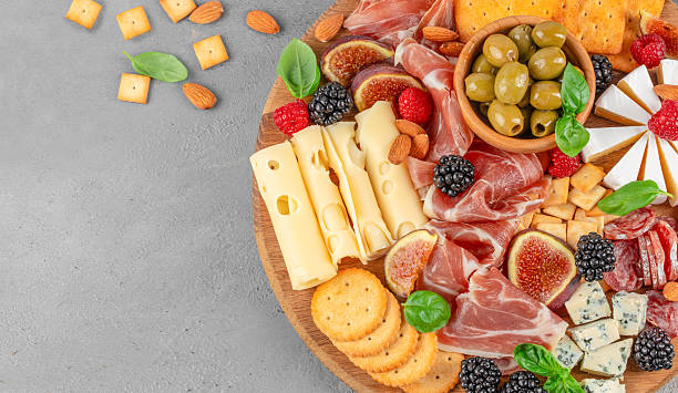 istock Gourmet charcuterie board with cheese, prosciutto, figs, olives, berries and crackers on a light textured background, top view, copy space 2248077102