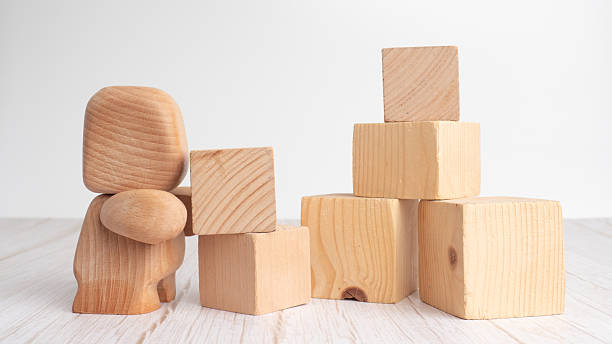 istock Wooden toy figure stacking cubes on wooden surface 2248078729
