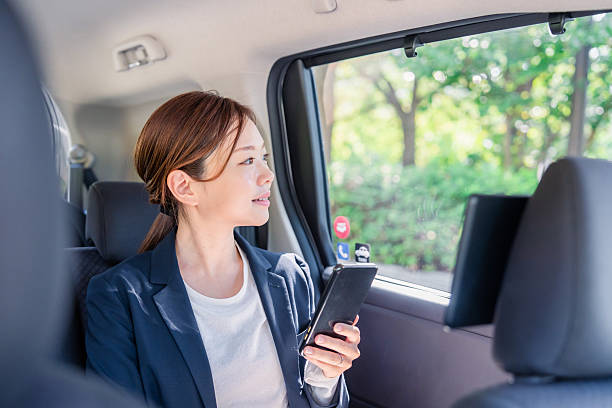 istock Young female businessperson using a smartphone in a cab 2248083439