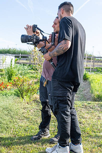 Two videographers filming with professional camera and gimbal in a garden