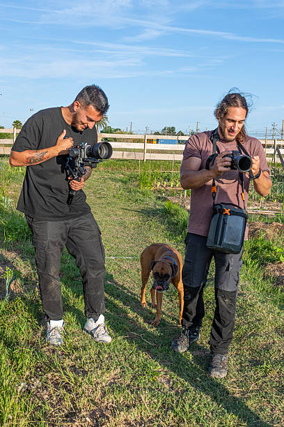 Two videographers filming in a garden with a boxer dog