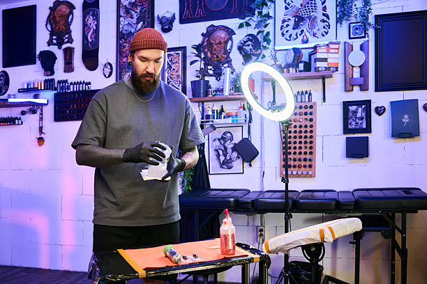 istock Middle Aged Caucasian Man Wearing Gloves Sanitizing Hands in Tattoo Studio 2248085110