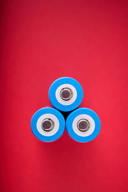 Close up of three blue rechargeable lithium batteries, size 18650, on a red table.