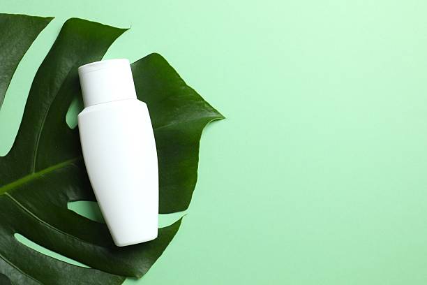 istock Cosmetic bottle with monstera leaf on colored background 2248087980