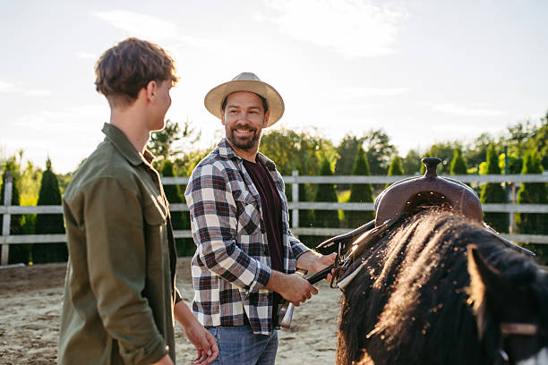 ather and son preparing, saddling horse for riding.