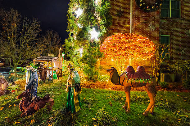 A festive outdoor scene featuring a holiday display with illuminated trees, a camel statue, and colorful figures in a brick-walled yard, capturing warm, joyful Christmas spirit at night.Brooklyn, NYC, USA
