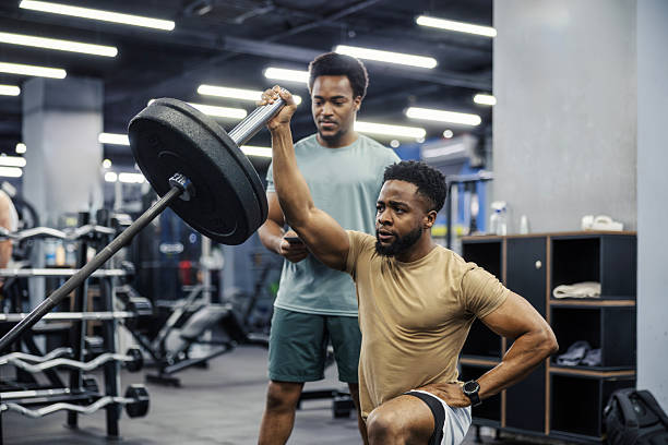 istock Personal trainer helping man with heavy barbell workout in gym 2248093333