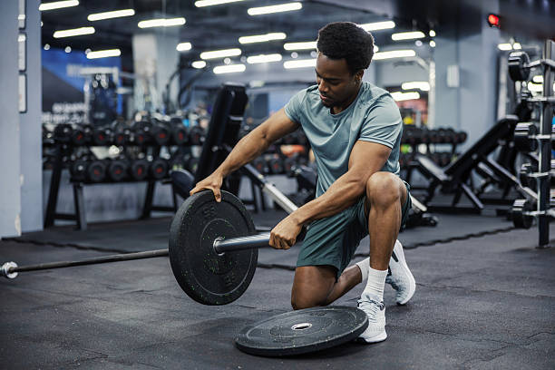 istock Young adult man preparing barbell for weightlifting exercise 2248093340