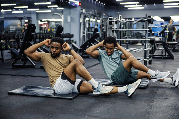 istock Two men doing sit-ups together in modern gym 2248093475