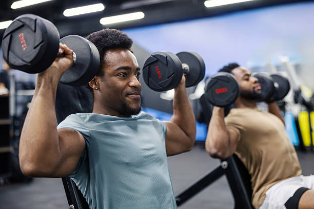 istock Two men doing dumbbell shoulder press at gym 2248095139