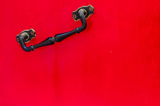 A vivid red door features a classic black metal handle, creating a bold focal point. The image conveys warmth and invitation, suitable for home, design, or branding contexts.