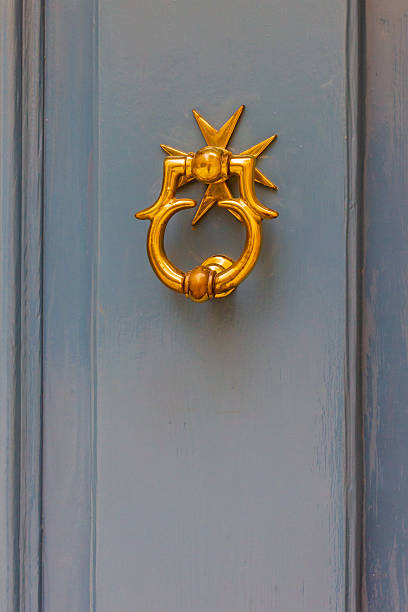 Luxurious brass door knocker with starburst motif against a classic blue front door. A timeless, welcoming architectural detail that adds vintage charm and warm curb appeal to a home.