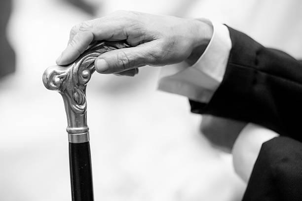 The cane suggests authority and tradition, while the steady hand indicates control and dignity. It can represent a patriarch preparing, a respected figure assuming his role, or the silent moment before an important event. It evokes Victorian/Edwardian aesthetics, a symbol of social standing.