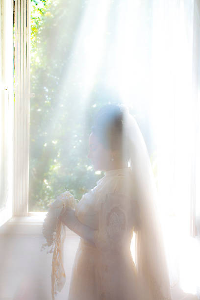 istock The bride is silhouetted against the light, enveloped by an intense light entering through the window, creating an ethereal and almost celestial atmosphere. The costume evokes the Belle Époque. The image oscillates between the real and the dreamlike. 2248096159