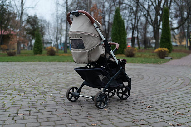 istock An empty stroller is parked beside a paved path in a peaceful park. Nearby trees show autumn colors, creating a calm environment in the afternoon 2248097688