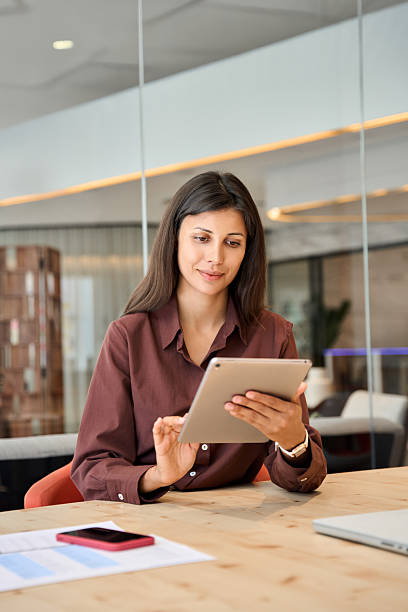 istock Successful latin hispanic young woman using pad computer for business app. Busy executive CEO businesswoman professional holding digital tablet pc device for work in modern office workplace. Vertical 2248098567