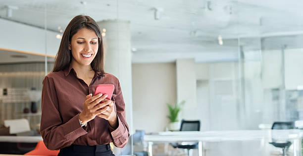 istock Young business woman manager user using cell phone mobile app. Smiling Latin Hispanic mature female businesswoman holding smartphone in office trading, working online at workspace. Banner, copy space 2248098587