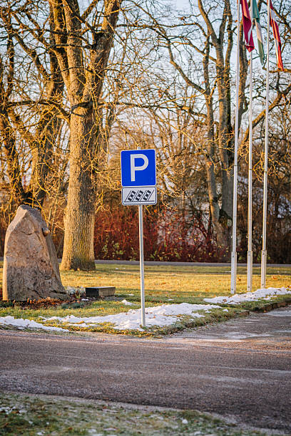 istock Parking sign stands prominently in a serene outdoor setting, surrounded by trees and flags, indicating designated parking area in a peaceful environment 2248102385