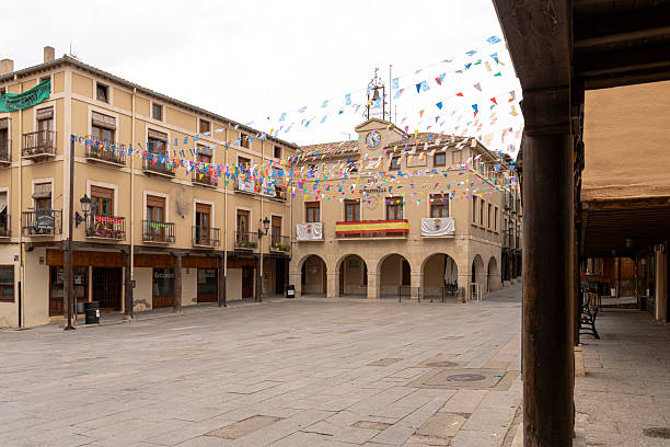 San Estaban de Gormaz, Soria, Spain, September 8, 2025; Main square of San Esteban de Gormaz in the province of Soria, Spain, with a historic building featuring arcades and a clock tower, all decorated with festive flags during the day, creating a peaceful village atmosphere.