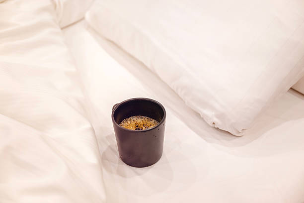 Black Cup of coffee on white sheets in the bed