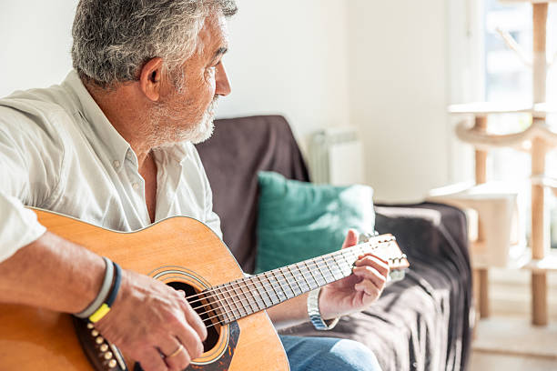 istock Senior man playing acoustic guitar at home 2248106448