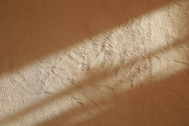 istock Sunlight casts soft shadows on textured earthy wall in warm tones during late afternoon 2248106738