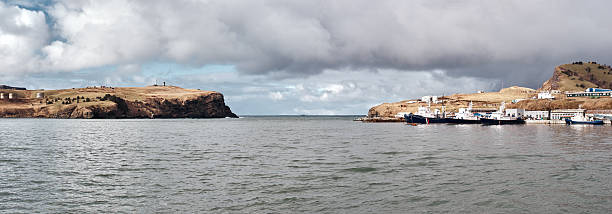 Sea ​​strait and moored ships in Malokurilskoye Bay. Malokurilskoye village. Southern Kuril islands. Shikotan island - one of the bigger islands of the Kuril Islands.