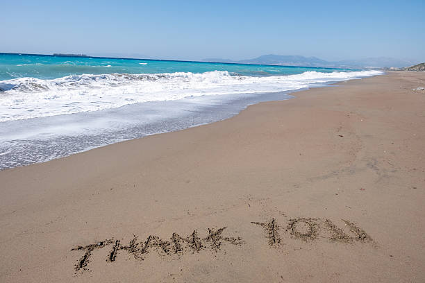 Words spelled out using small stones on a sandy surface. The message reads \