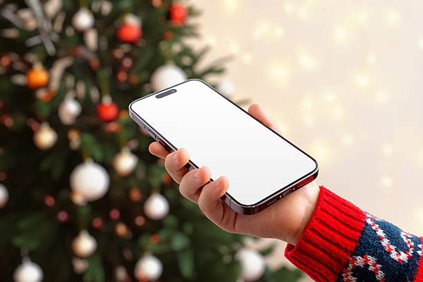 istock Girl using smartphone with blank screen in front of Christmas tree, ideal for app mockups, festive campaigns, mobile UI showcases and holiday marketing 2248109968