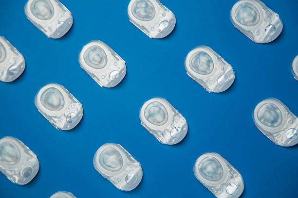 istock Coloring diagonally: one-day contact lenses lie diagonally in a disposable protective case, in which transparent lenses float, which lie on a blue background at the same distance. The concept of ophthalmology, vision correction, eye care. 2248115525