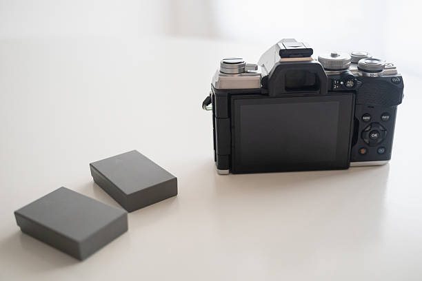 A close-up of two hands holding a digital camera with a blank white screen.
