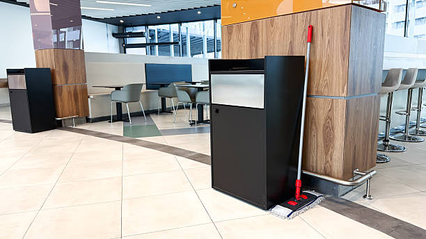 istock Clean modern cafeteria interior with empty tables, trash bins and a mop placed against a wooden column in a well-lit spacious area 2248122360