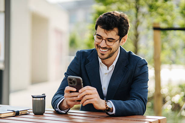 istock Businessman smiling working on mobile phone outdoors 2248123125