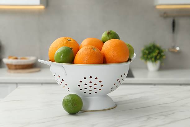 istock Colander with fresh fruits on white marble table in kitchen 2248131855