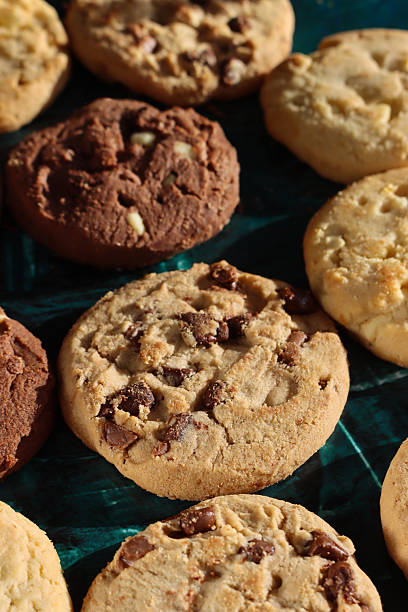 istock Full frame image of rounds of chocolate chip shortbread biscuits, rows of triple chocolate chip, milk chocolate chip and white chocolate chip cookies, mottled green background, elevated view, home baking concept 2248132948
