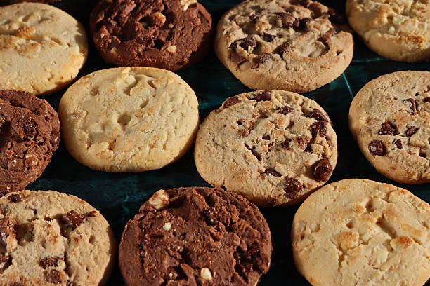 istock Full frame image of rounds of chocolate chip shortbread biscuits, rows of triple chocolate chip, milk chocolate chip and white chocolate chip cookies, mottled green background, elevated view, home baking concept 2248132962