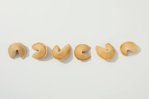 Several individually wrapped fortune cookies resting on a white plate, placed atop a black and white floral tablecloth, invite anticipation and enjoyment as sweet treats await discovery