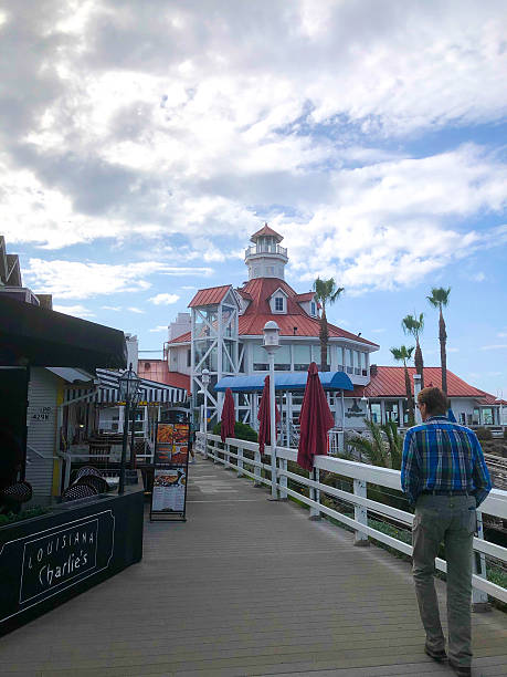 Long Beach, CA, USA - November 13, 2025: A man walks on the boardwalk at Shoreline Village at Rainbow Harbor near downtown Long Beach.