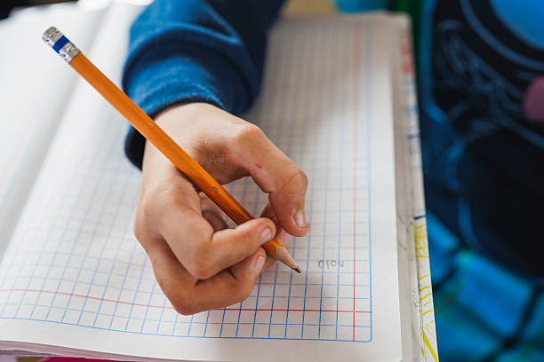 istock Child hand writing homework in school notebook with pencil 2248138257