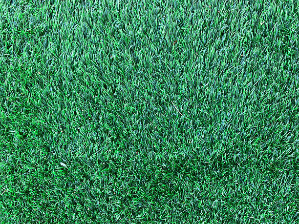 Close up view of vibrant green artificial turf, showcasing its synthetic blades and realistic texture for durable landscaping solutions