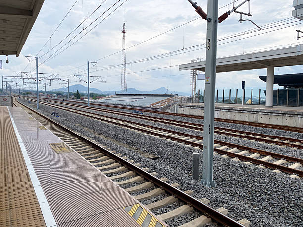 istock Modern High speed Train Station Platform with Multiple Railway Tracks and Overhead Power Lines Under a Cloudy Sky, Showcasing Infrastructure 2248141114