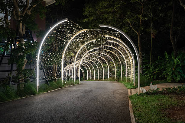 Curved white beams form an illuminated tunnel accented with hanging lights, and the structural lines create a clean pattern against the dark background.