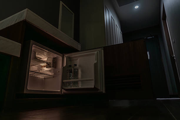 istock A small fridge glows softly in a dim hotel room as its open door reveals interior lighting. The low-angle view highlights the contrast between darkness and warm light. 2248146428