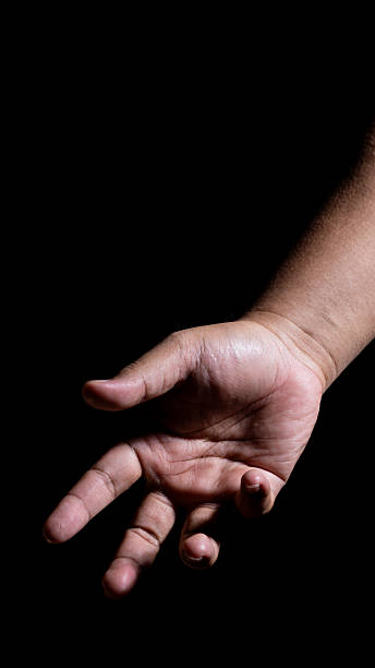 istock A hand extended forward in a low-key studio setup, palm facing outward with strong highlights and shadows, conveying offering, communication, or expressive movement in dark space. 2248146890