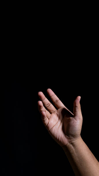 A softly lit hand forming a gentle upward gesture against a black background, creating a calm, expressive pose ideal for themes of invitation, openness, or subtle communication.