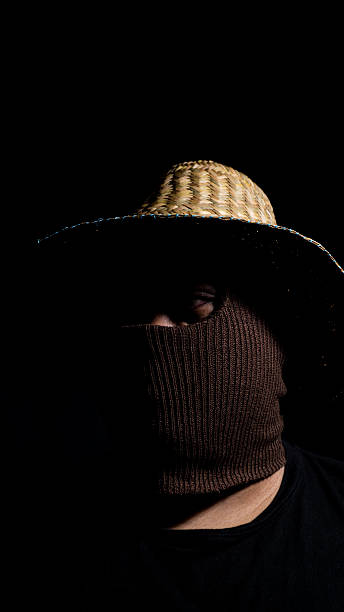 istock Portrait of a balaclava-covered face under a woven hat, with deep shadows concealing most features. A mix of rustic and mysterious elements creates a unique dramatic visual. 2248147009