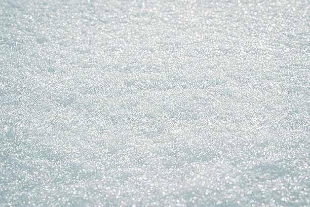 Sparkling crystals of fresh snow under bright sunlight create a soft atmosphere of winter purity and natural texture