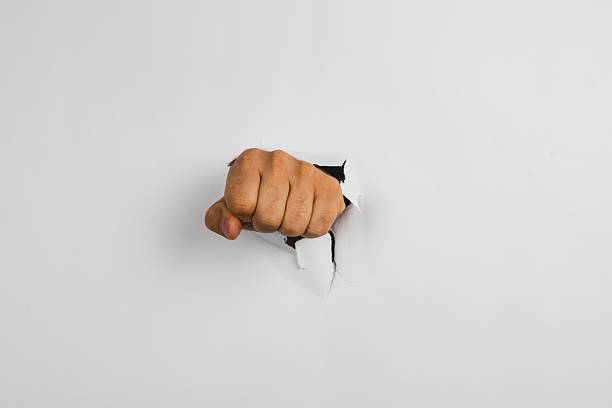 Fist breaking through white wall in a dramatic expression of strength