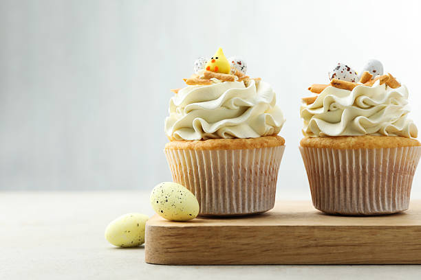 istock Tasty Easter cupcakes with vanilla cream and candies on gray table, space for text 2248152558