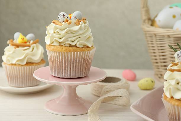istock Tasty Easter cupcakes with vanilla cream on light wooden table 2248152656